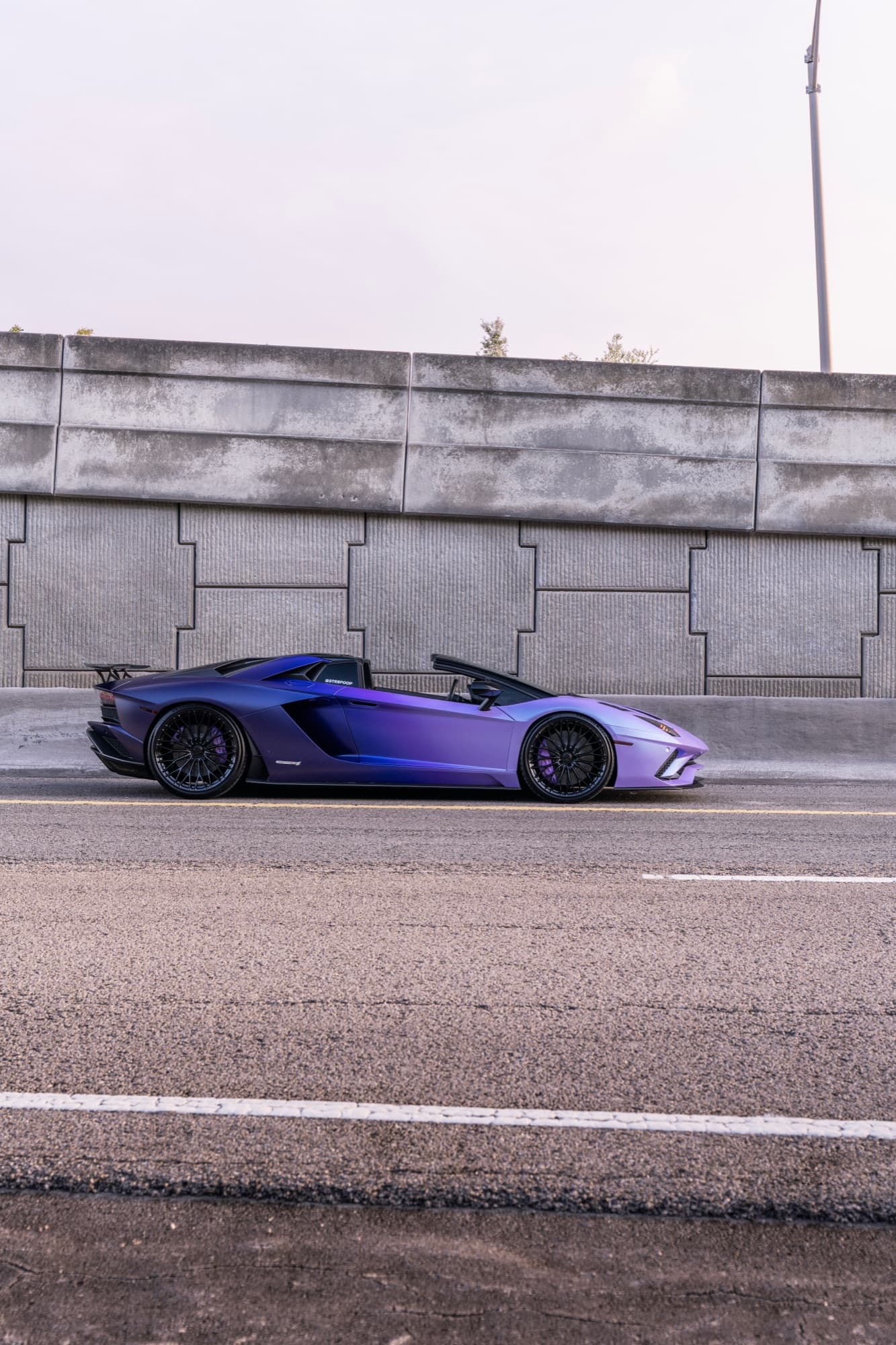 Lamborghini Aventador S Roadster side profile against concrete wall